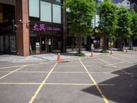 yellow marking is in the parking space by the tall building and red cones are on the pavement