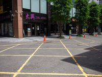 yellow marking is in the parking space by the tall building and red cones are on the pavement