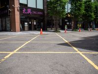 yellow marking is in the parking space by the tall building and red cones are on the pavement