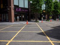 yellow marking is in the parking space by the tall building and red cones are on the pavement