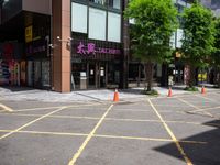 yellow marking is in the parking space by the tall building and red cones are on the pavement