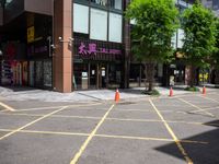 yellow marking is in the parking space by the tall building and red cones are on the pavement