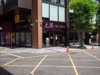 yellow marking is in the parking space by the tall building and red cones are on the pavement