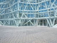 a building made of glass and steel has glass in it, but the surrounding area is mostly brick