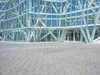 a building made of glass and steel has glass in it, but the surrounding area is mostly brick