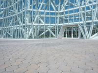 a building made of glass and steel has glass in it, but the surrounding area is mostly brick