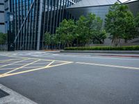 a parking lot with a building on the side of it and trees on the corner