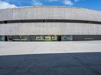 the circular concrete building has two floors and four columns on each floor, under a large white circular roof