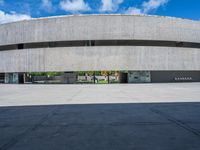 the circular concrete building has two floors and four columns on each floor, under a large white circular roof