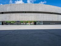 the circular concrete building has two floors and four columns on each floor, under a large white circular roof