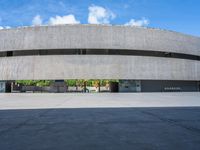 the circular concrete building has two floors and four columns on each floor, under a large white circular roof