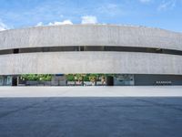 the circular concrete building has two floors and four columns on each floor, under a large white circular roof