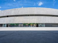 the circular concrete building has two floors and four columns on each floor, under a large white circular roof