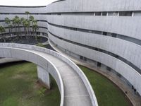 a concrete building and walkway with curved walls leading into the building and trees at either side of it