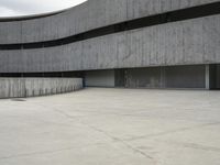 a building with cement roof near green grass and lawn in front of it, under a gray sky