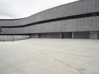 a building with cement roof near green grass and lawn in front of it, under a gray sky