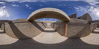 the sun shines through the curved concrete structure of an open air museum building in the desert