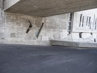 the large grey building features a long concrete wall with columns and a curved concrete bench below