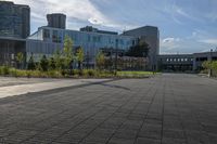 a city street surrounded by grass and tall buildings at the end of a street there is a paved pathway in front of the building