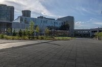 a city street surrounded by grass and tall buildings at the end of a street there is a paved pathway in front of the building