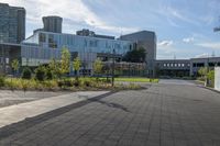 a city street surrounded by grass and tall buildings at the end of a street there is a paved pathway in front of the building