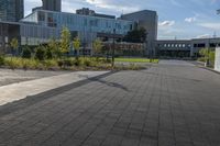 a city street surrounded by grass and tall buildings at the end of a street there is a paved pathway in front of the building