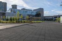 a city street surrounded by grass and tall buildings at the end of a street there is a paved pathway in front of the building