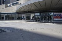 a person sitting at the bench in front of a mall that is empty of people