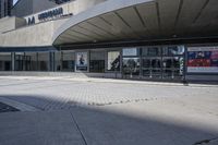 a person sitting at the bench in front of a mall that is empty of people