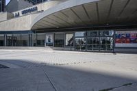 a person sitting at the bench in front of a mall that is empty of people