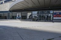 a person sitting at the bench in front of a mall that is empty of people