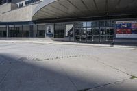 a person sitting at the bench in front of a mall that is empty of people