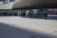 a person sitting at the bench in front of a mall that is empty of people