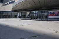 a person sitting at the bench in front of a mall that is empty of people