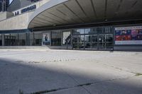 a person sitting at the bench in front of a mall that is empty of people