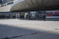 a person sitting at the bench in front of a mall that is empty of people