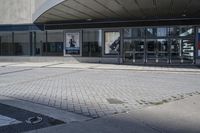 a person sitting at the bench in front of a mall that is empty of people