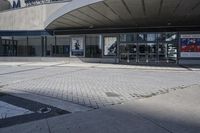 a person sitting at the bench in front of a mall that is empty of people