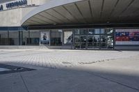 a person sitting at the bench in front of a mall that is empty of people