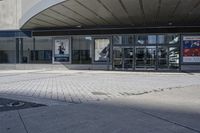 a person sitting at the bench in front of a mall that is empty of people