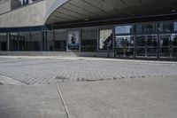 a person sitting at the bench in front of a mall that is empty of people