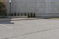 an empty parking lot next to a tall building in a parking lot with trees growing on the ground