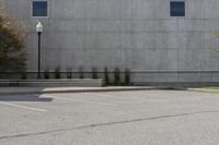 an empty parking lot next to a tall building in a parking lot with trees growing on the ground