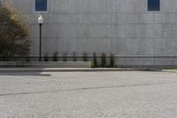 an empty parking lot next to a tall building in a parking lot with trees growing on the ground