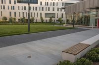 a city street surrounded by grass and tall buildings at the end of a street there is a paved pathway in front of the building