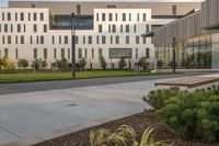 a city street surrounded by grass and tall buildings at the end of a street there is a paved pathway in front of the building