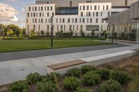 a city street surrounded by grass and tall buildings at the end of a street there is a paved pathway in front of the building