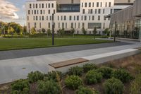 a city street surrounded by grass and tall buildings at the end of a street there is a paved pathway in front of the building