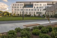 a city street surrounded by grass and tall buildings at the end of a street there is a paved pathway in front of the building