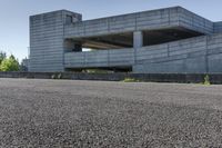 a concrete building sits at the top of a hill with concrete walls and pillars built over it